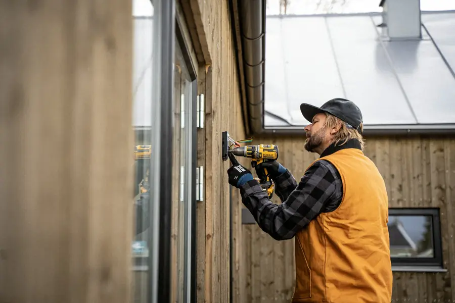 Electrician fitting an outdoor socket on a house